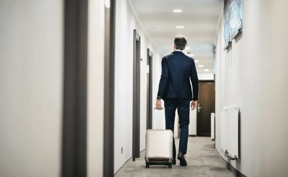 Businessman walking with luggage in a hotel corridor